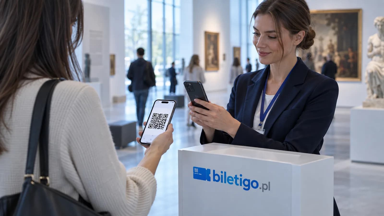 Obsługa muzeum skanuje telefonem kod QR z biletu zwiedzającej przy stanowisku wejścia